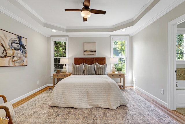 bedroom featuring multiple windows, light wood-type flooring, a tray ceiling, baseboards, and recessed lighting