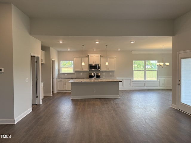 kitchen with a sink, white cabinetry, stainless steel microwave, and a chandelier