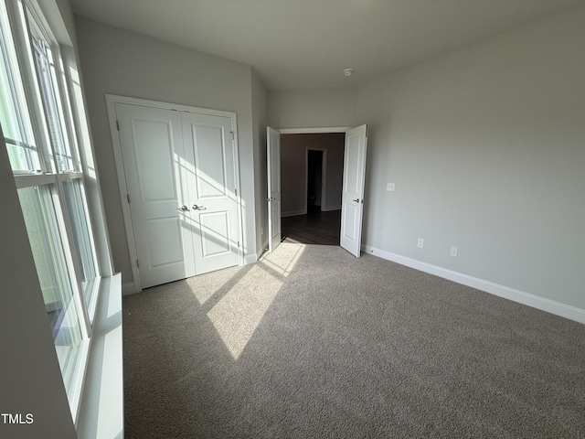 unfurnished bedroom featuring baseboards, carpet, and a closet