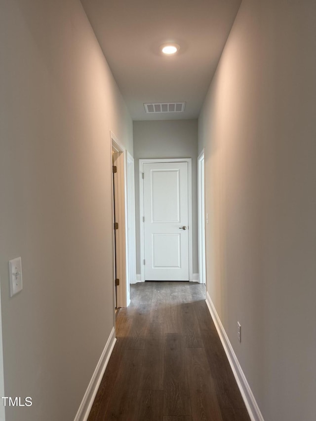 corridor with visible vents, dark wood-style flooring, and baseboards