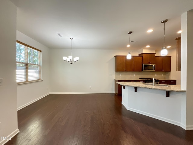 kitchen featuring a sink, brown cabinetry, dark wood-type flooring, stainless steel microwave, and recessed lighting