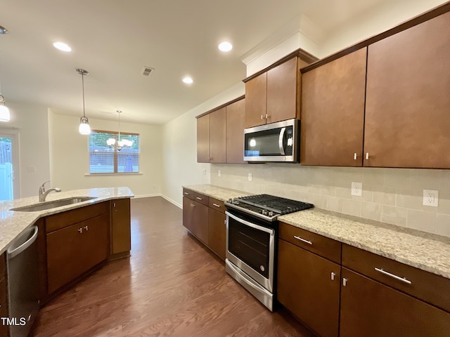 kitchen featuring a sink, stainless steel appliances, decorative backsplash, a chandelier, and dark wood-style floors