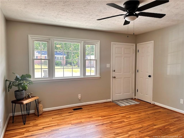 spare room featuring light wood-style floors, a textured ceiling, and baseboards