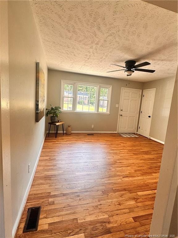 interior space featuring visible vents, a textured ceiling, ceiling fan, and light wood-style floors