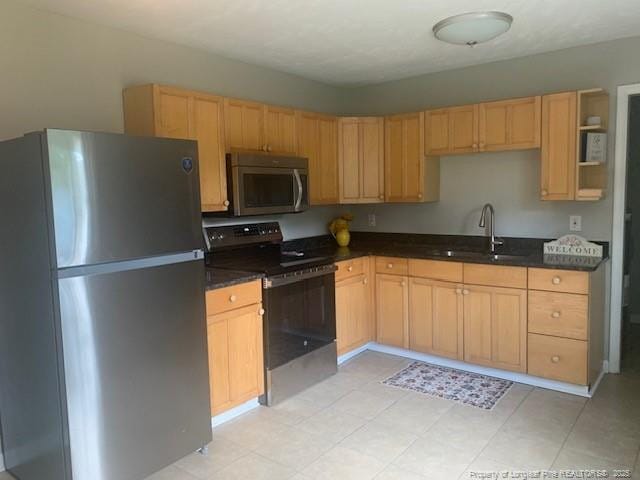 kitchen with a sink, dark countertops, light brown cabinetry, and stainless steel appliances