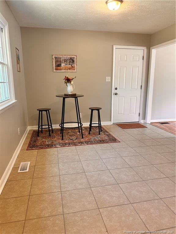 entrance foyer featuring baseboards, a textured ceiling, visible vents, and light tile patterned floors