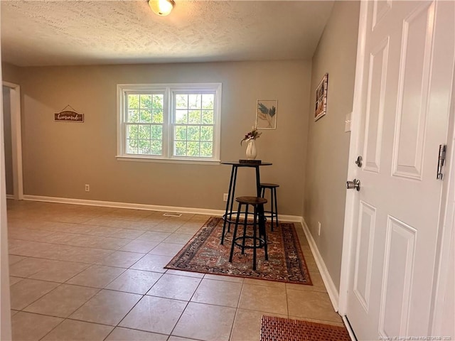 dining room featuring baseboards, a textured ceiling, and light tile patterned floors