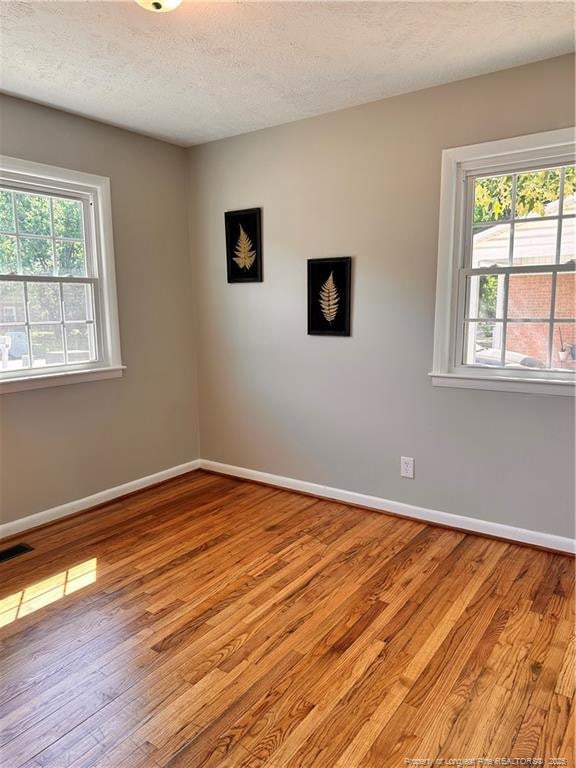 spare room with baseboards, visible vents, a healthy amount of sunlight, and light wood-style flooring