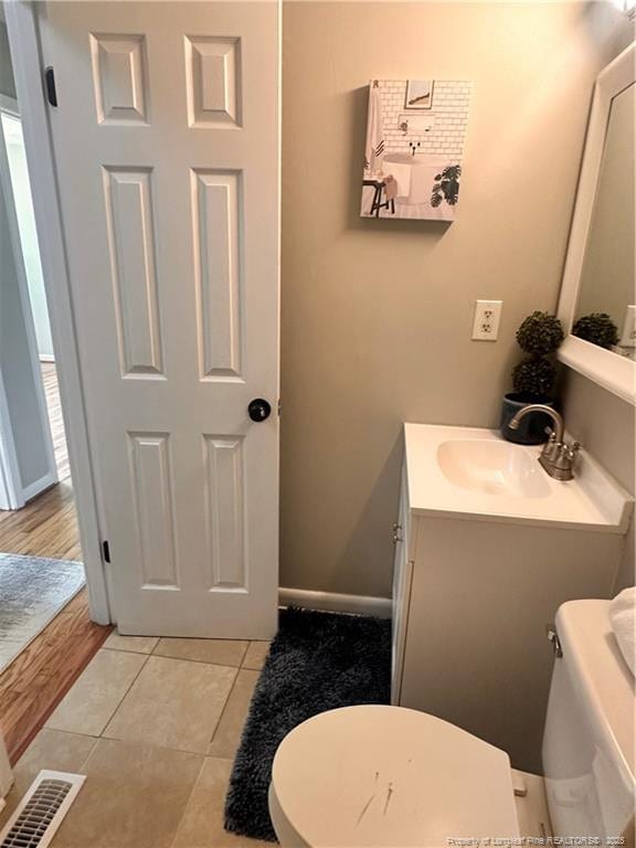bathroom with toilet, visible vents, tile patterned flooring, and vanity