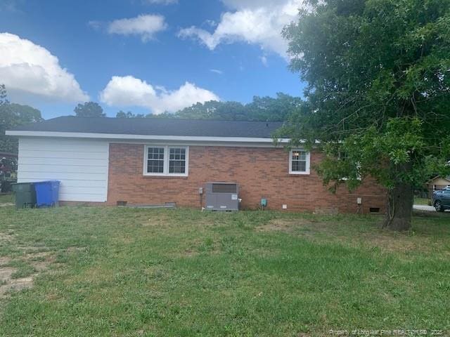 back of house with a lawn, brick siding, and crawl space