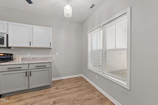 kitchen with electric range oven, light wood finished floors, baseboards, stainless steel microwave, and gray cabinetry