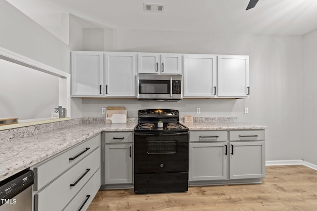 kitchen featuring appliances with stainless steel finishes, light wood finished floors, light stone countertops, gray cabinetry, and baseboards