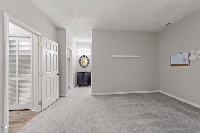 unfurnished bedroom featuring baseboards, carpet, a textured ceiling, and ensuite bath