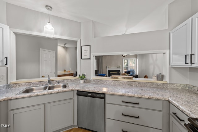 kitchen with appliances with stainless steel finishes, a sink, a fireplace, pendant lighting, and gray cabinets