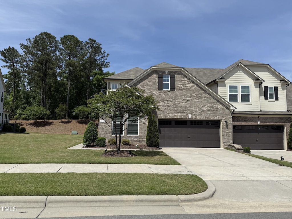 craftsman-style house featuring brick siding, driveway, a garage, and a front lawn