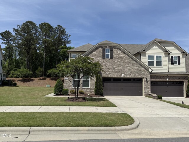 craftsman-style house featuring brick siding, driveway, a garage, and a front lawn