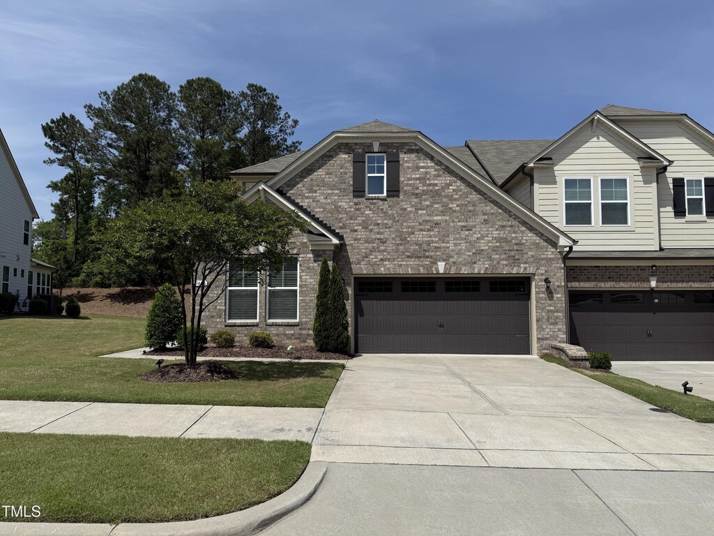 view of front of home featuring brick siding, driveway, a front yard, and a garage
