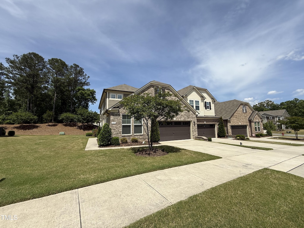 view of front of home featuring stone siding, concrete driveway, a front yard, and an attached garage