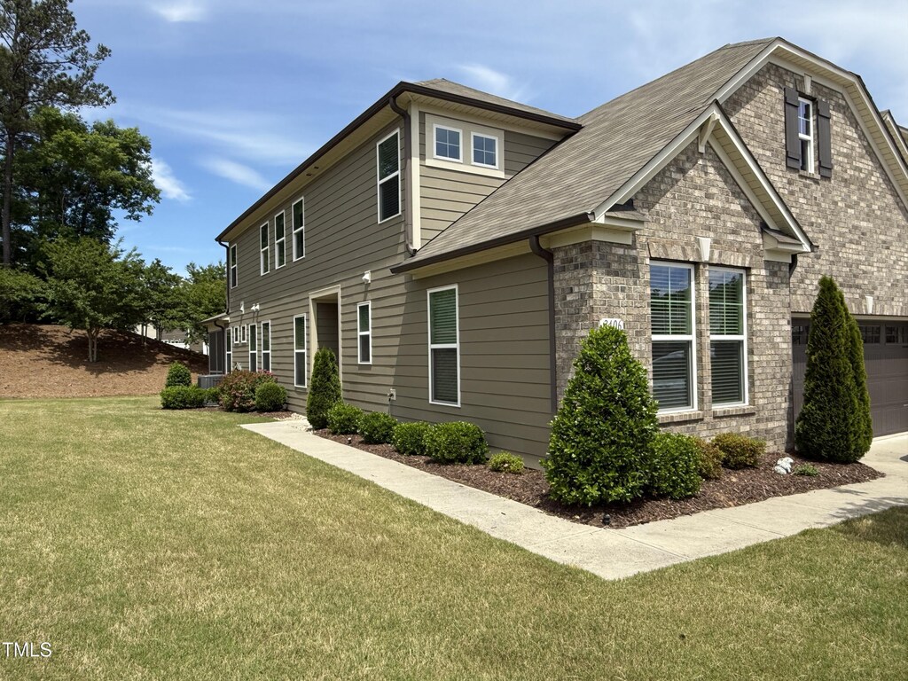 view of property exterior featuring a yard, roof with shingles, and stone siding