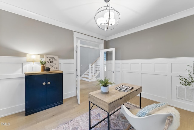 office with light wood-style floors, a wainscoted wall, a decorative wall, and a chandelier