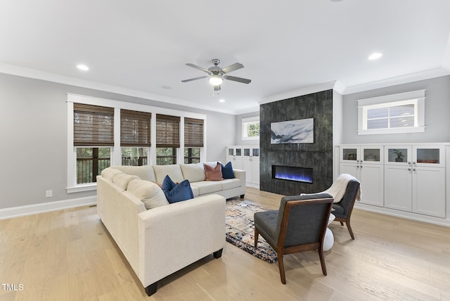 living room with crown molding, a ceiling fan, and light wood-style flooring