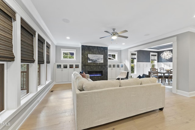 living room with crown molding, a large fireplace, and light wood finished floors