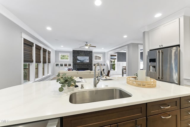 kitchen with a sink, ceiling fan, a high end fireplace, light countertops, and high end refrigerator
