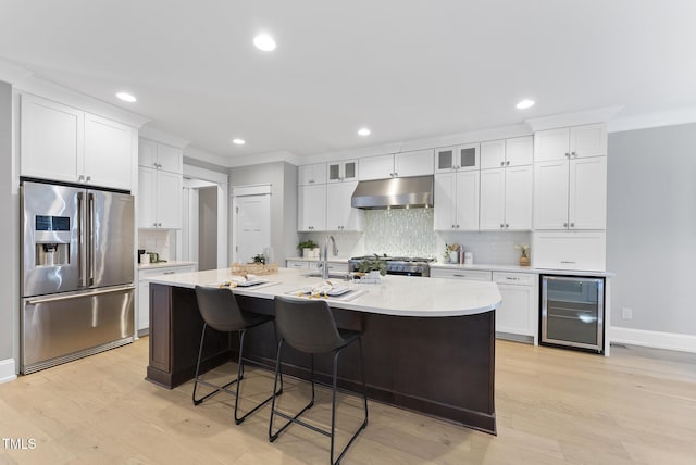 kitchen with wine cooler, high end fridge, stove, under cabinet range hood, and a sink