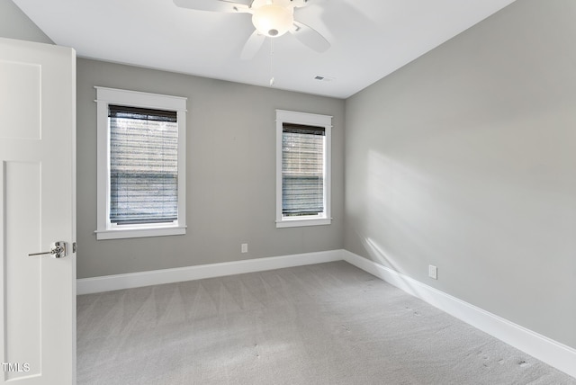 empty room with carpet floors, baseboards, ceiling fan, and visible vents