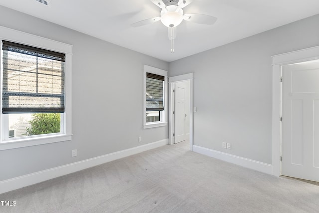 unfurnished bedroom with baseboards, ceiling fan, light carpet, and multiple windows