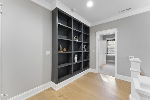 hallway with baseboards, visible vents, and light wood finished floors