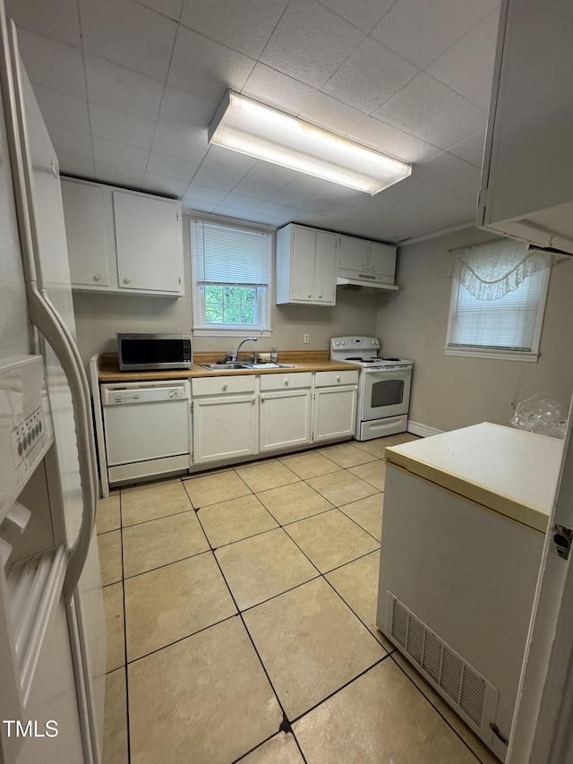 kitchen with a sink, light tile patterned floors, and white appliances