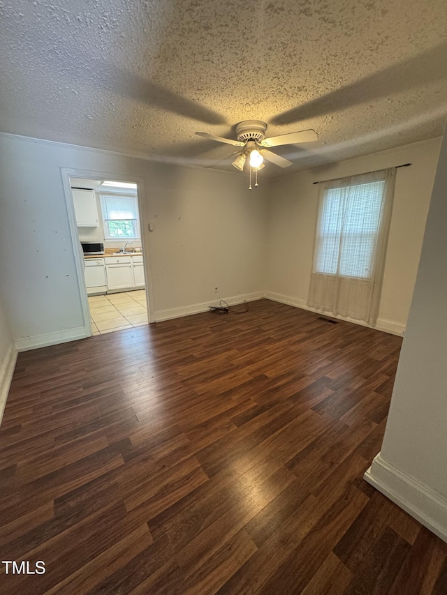 spare room with a ceiling fan, wood finished floors, baseboards, a textured ceiling, and a sink