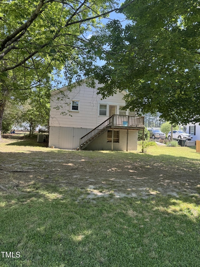 back of property with a lawn, a deck, and stairs