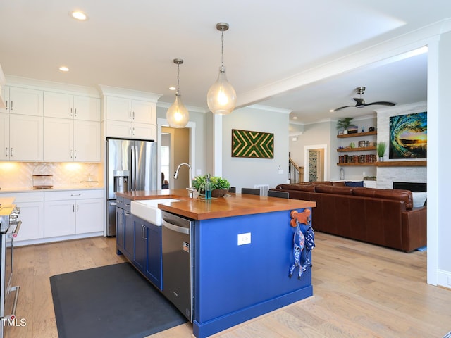1180 Duke Farm Dr, Wake Forest, NC 27587 - kitchen featuring stainless steel appliances, white cabinetry, blue cabinetry, wood counters, and a sink