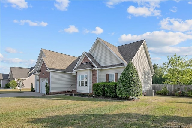 craftsman house with fence, a garage, a front yard, central air condition unit, and driveway