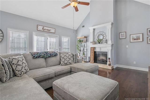 living room featuring a glass covered fireplace, baseboards, ceiling fan, high vaulted ceiling, and dark wood-type flooring