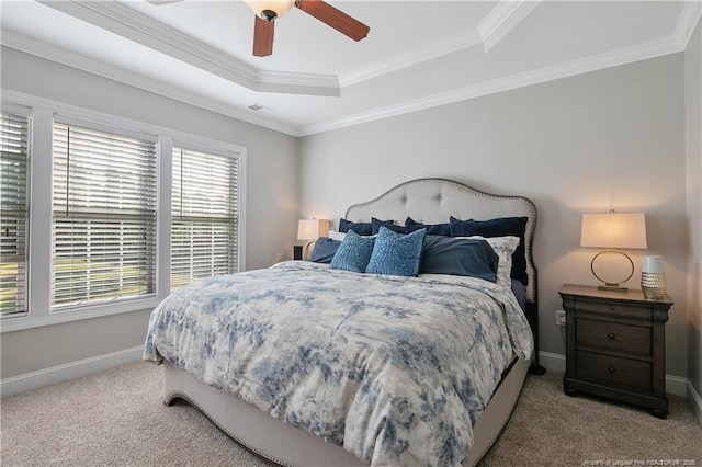 carpeted bedroom featuring visible vents, ornamental molding, baseboards, a raised ceiling, and a ceiling fan