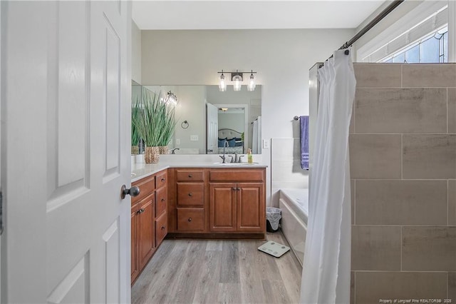 full bathroom featuring curtained shower, wood finished floors, a bath, and vanity