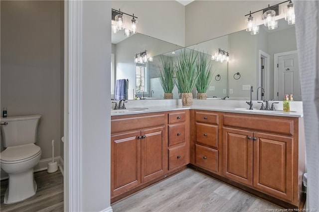 full bath featuring double vanity, a sink, wood finished floors, and toilet