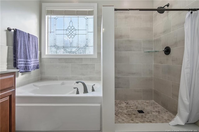 bathroom featuring a bath, a tile shower, and a healthy amount of sunlight