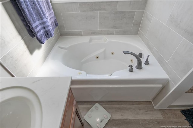 full bathroom featuring a tub with jets, wood finished floors, and vanity