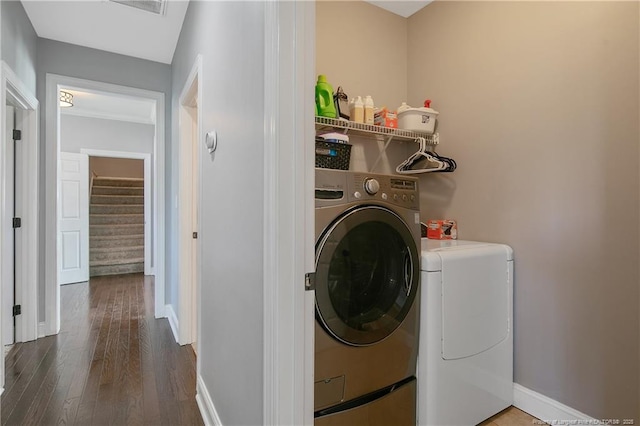 clothes washing area with baseboards, laundry area, wood finished floors, and washer and clothes dryer