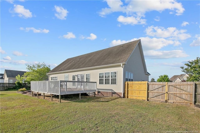 back of property featuring a yard, fence, a wooden deck, and a gate