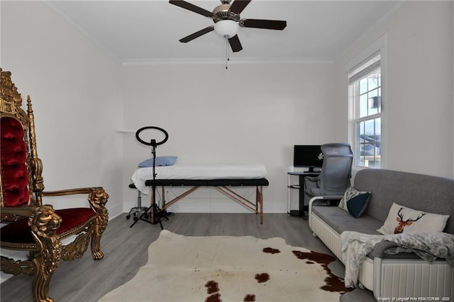 sitting room with crown molding, a ceiling fan, baseboards, and wood finished floors