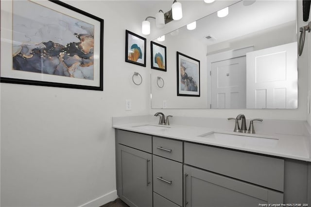 bathroom featuring double vanity, baseboards, visible vents, and a sink