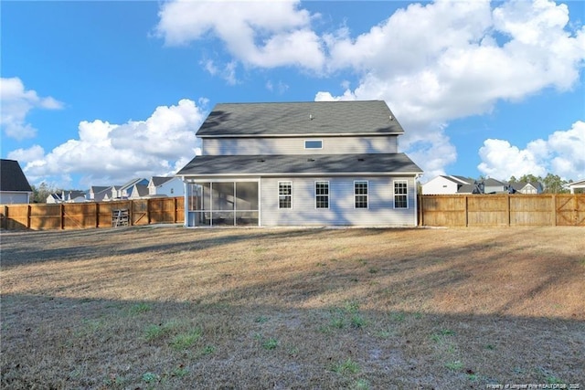rear view of property featuring a lawn, a fenced backyard, and a sunroom
