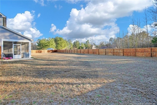 view of yard featuring a sunroom and a fenced backyard