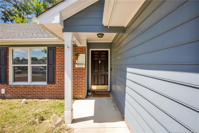 view of exterior entry featuring covered porch and brick siding