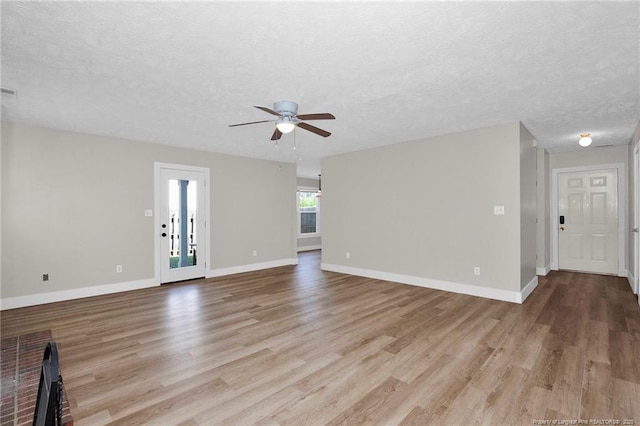 unfurnished living room featuring baseboards, a ceiling fan, a textured ceiling, and light wood-style flooring